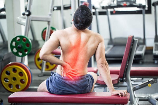 Man with back pain at fitness center in weight room